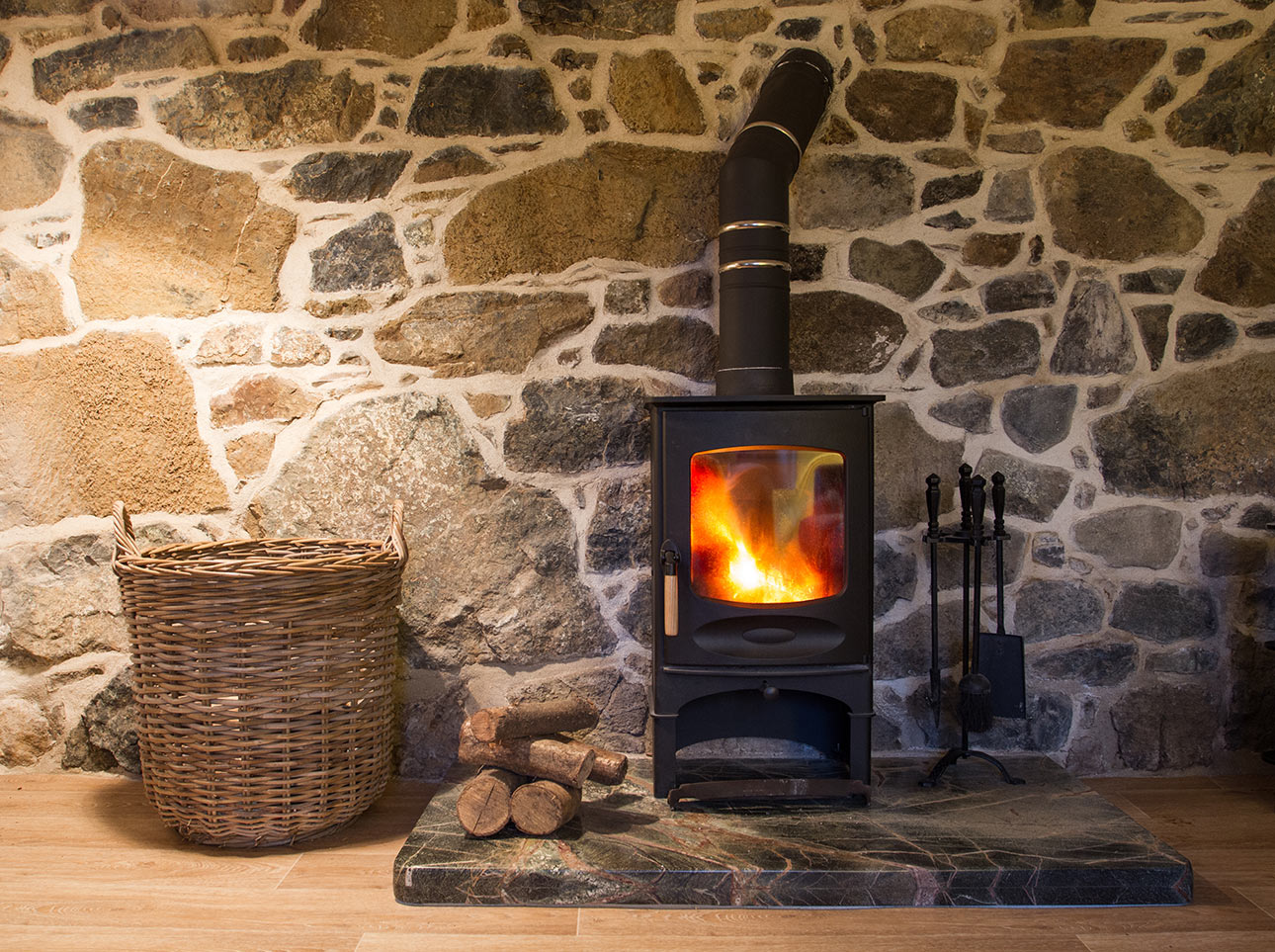 Wood-burning stove in front of a natural stone wall